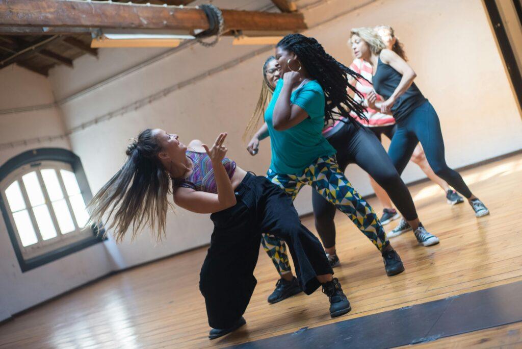 A diverse group of women of varying ages, sizes, and ethnicities dancing together in workout clothes.